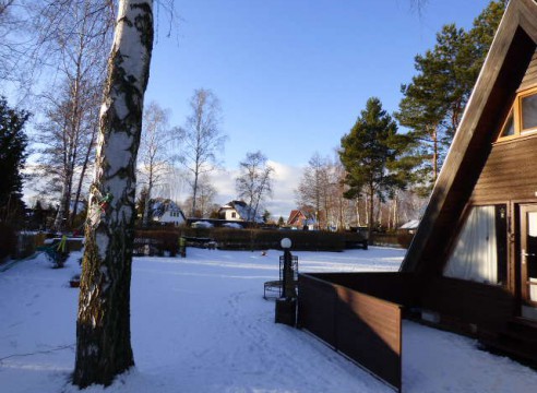 Finnhütte mit Reetdach auf großem Grundstück in Ferienhaussiedlung